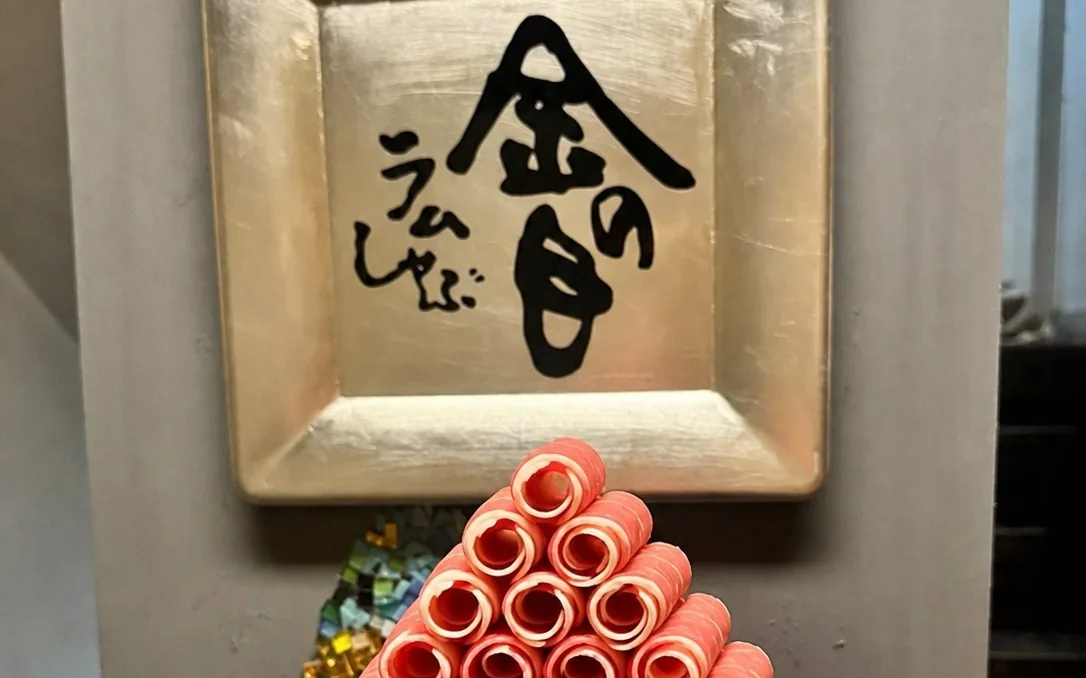 金色の『金の目 らむしゃぶ』の額を背に、ロールラムを円錐状に高く積み上げた盛り付け